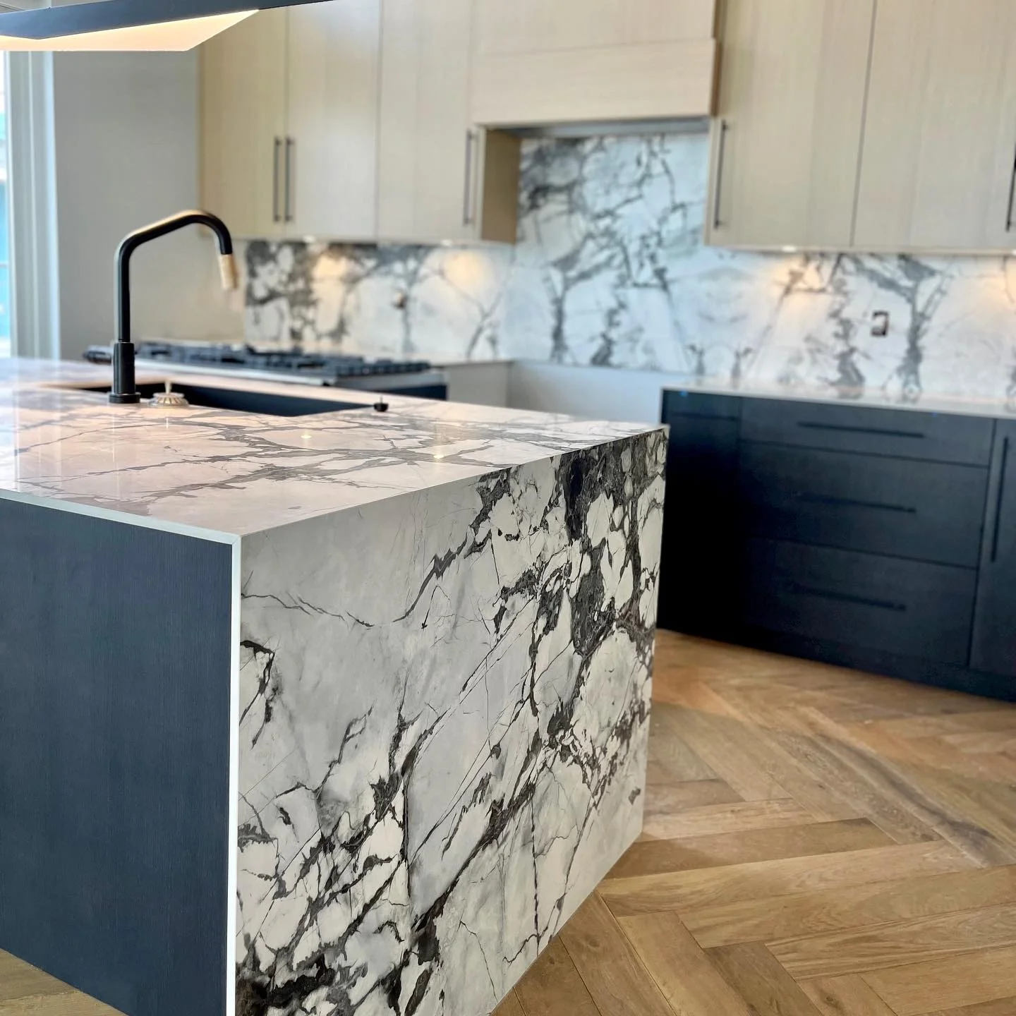 Kitchen with a dramatic veined natural stone waterfall island